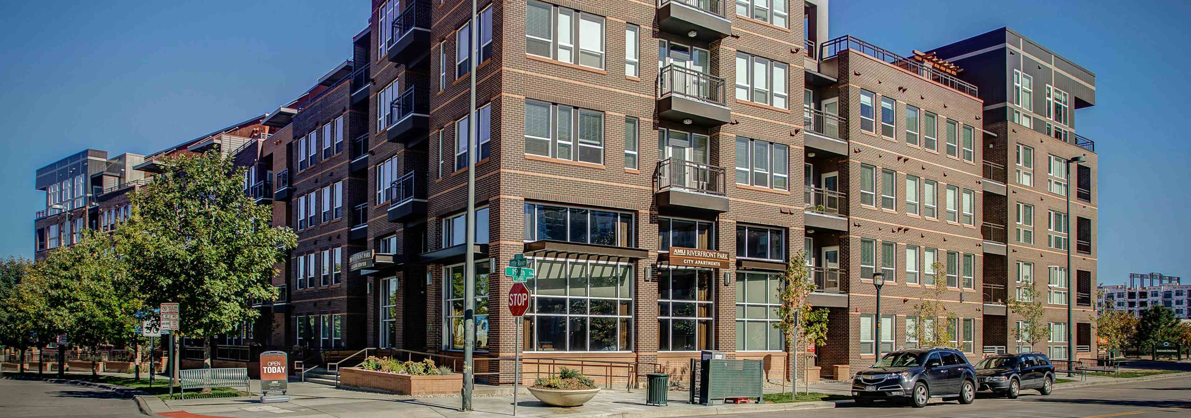 Exterior of AMLI Riverfront Park apartment building with a brick facade and balconies and a view of the street with cars