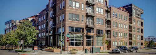 Exterior of AMLI Riverfront Park apartment building with a brick facade and balconies and a view of the street with cars