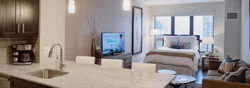 Interior view of AMLI River North studio layout with the kitchen connecting to a living and bedroom area with a large window