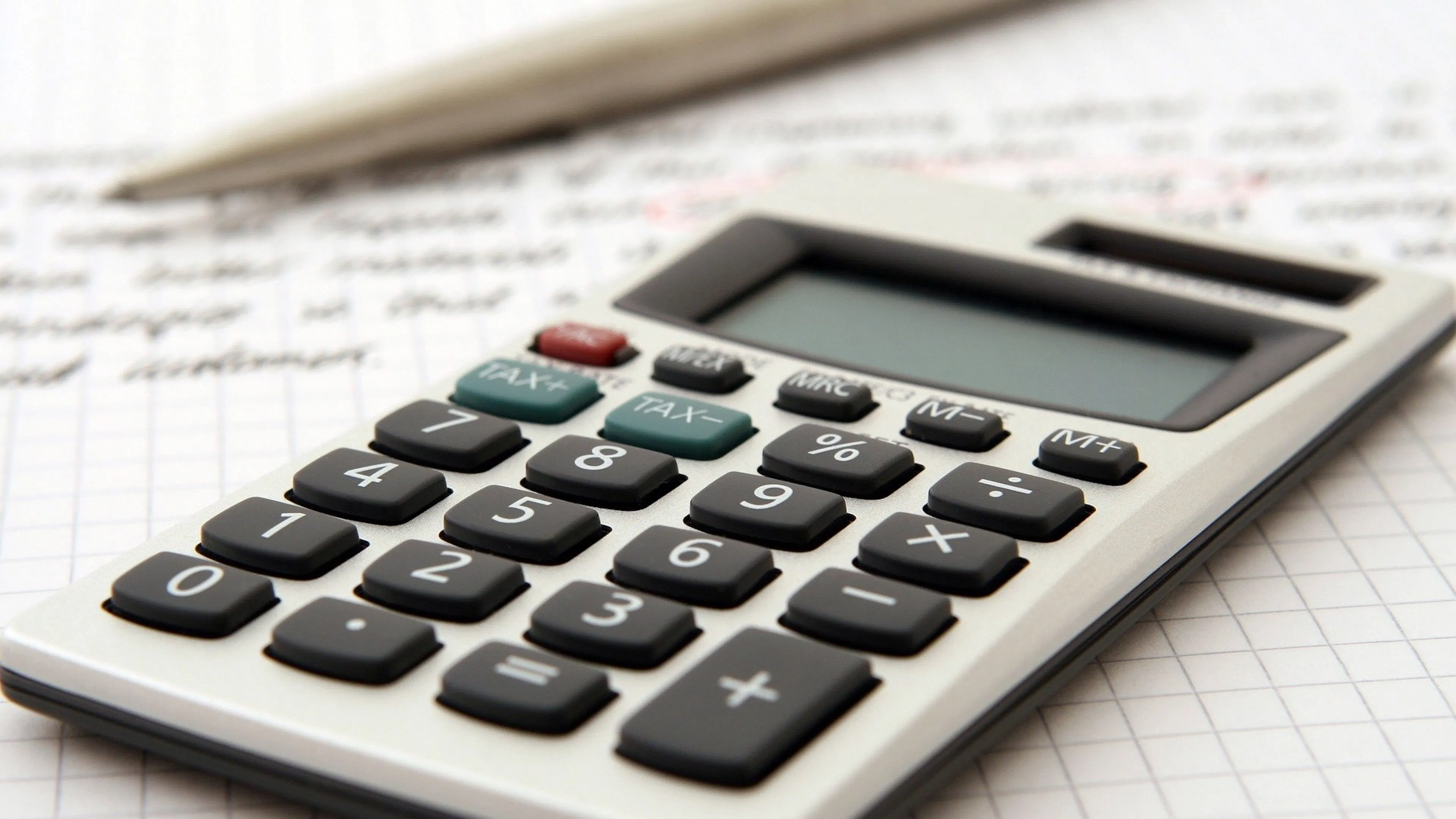 A simple hand held calculator resting on a piece of paper