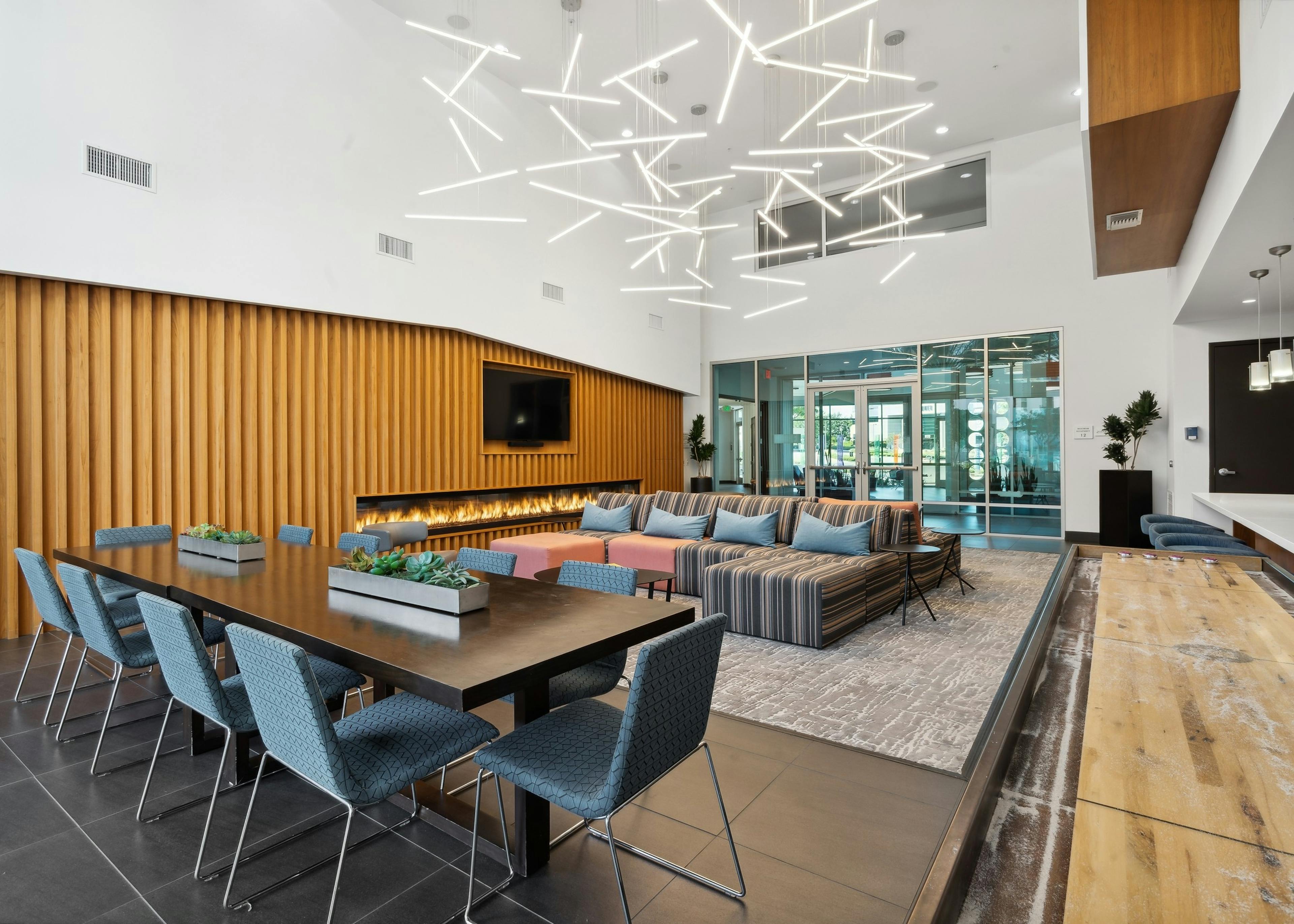 AMLI Uptown Orange clubroom with large dining table with chairs and couches and shuffleboard and lit fireplace
