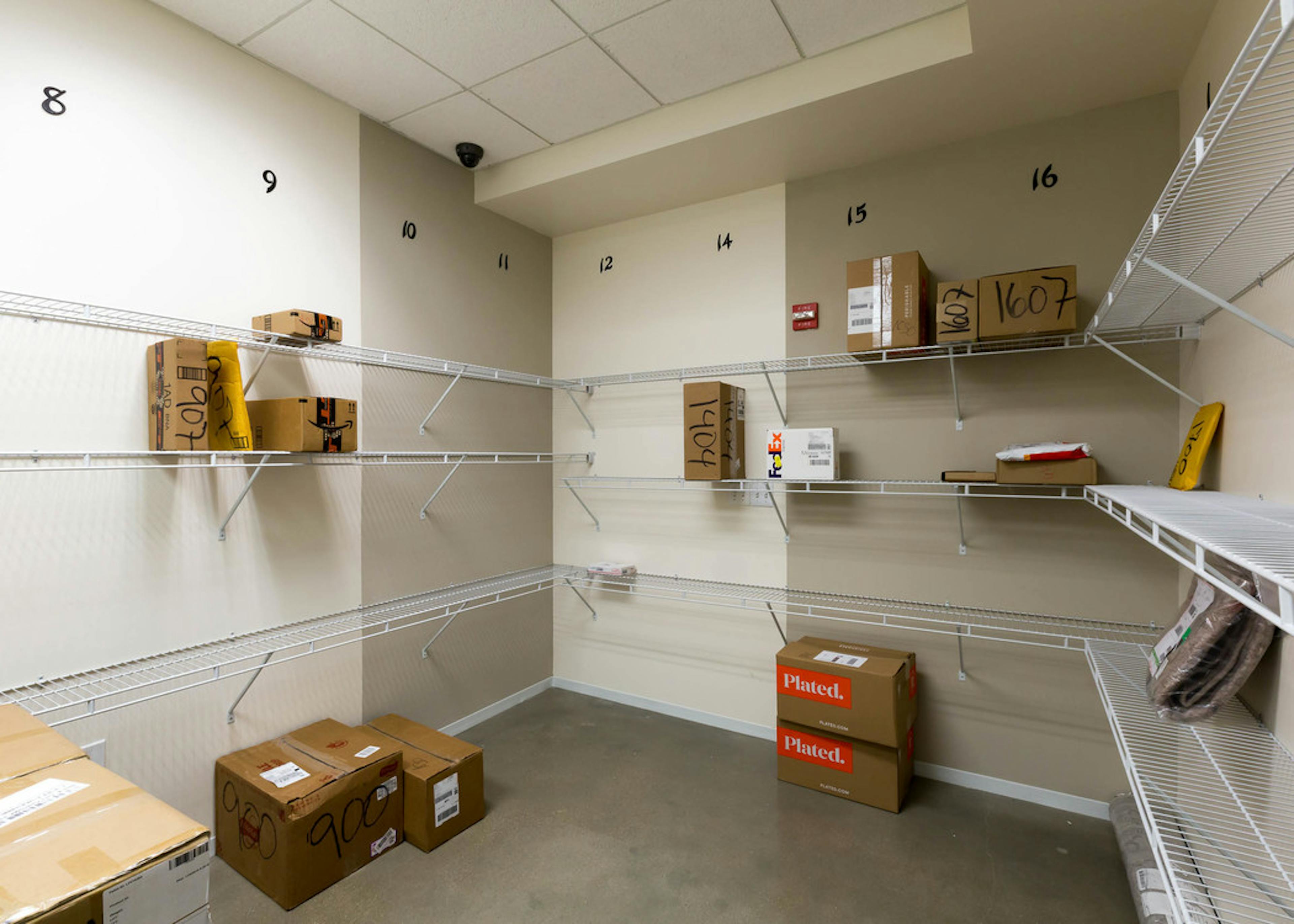 Interior view of package room at AMLI on 2nd with light walls and packages scattered along built in white shelving