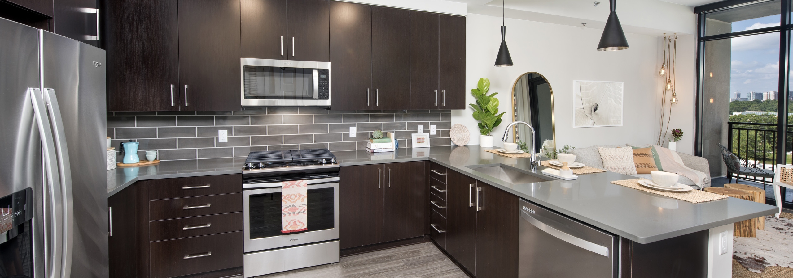 AMLI Lenox apartment kitchen with dark brown cabinets and stainless steel appliances and kitchen island and large window