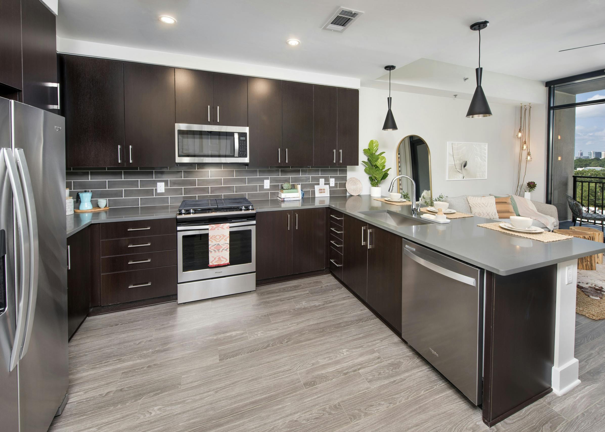 AMLI Lenox apartment kitchen with dark brown cabinets and stainless steel appliances and kitchen island and large window