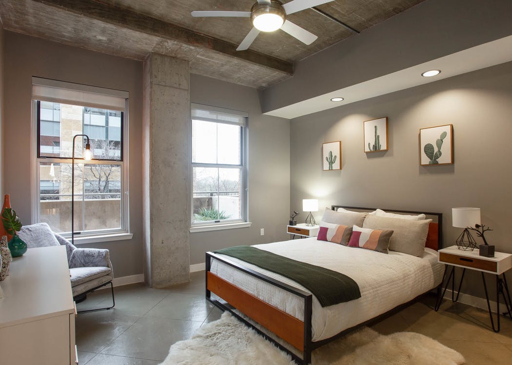 AMLI Downtown bedroom with grey walls and a comfy white bed in front of two large windows with a bright daytime view