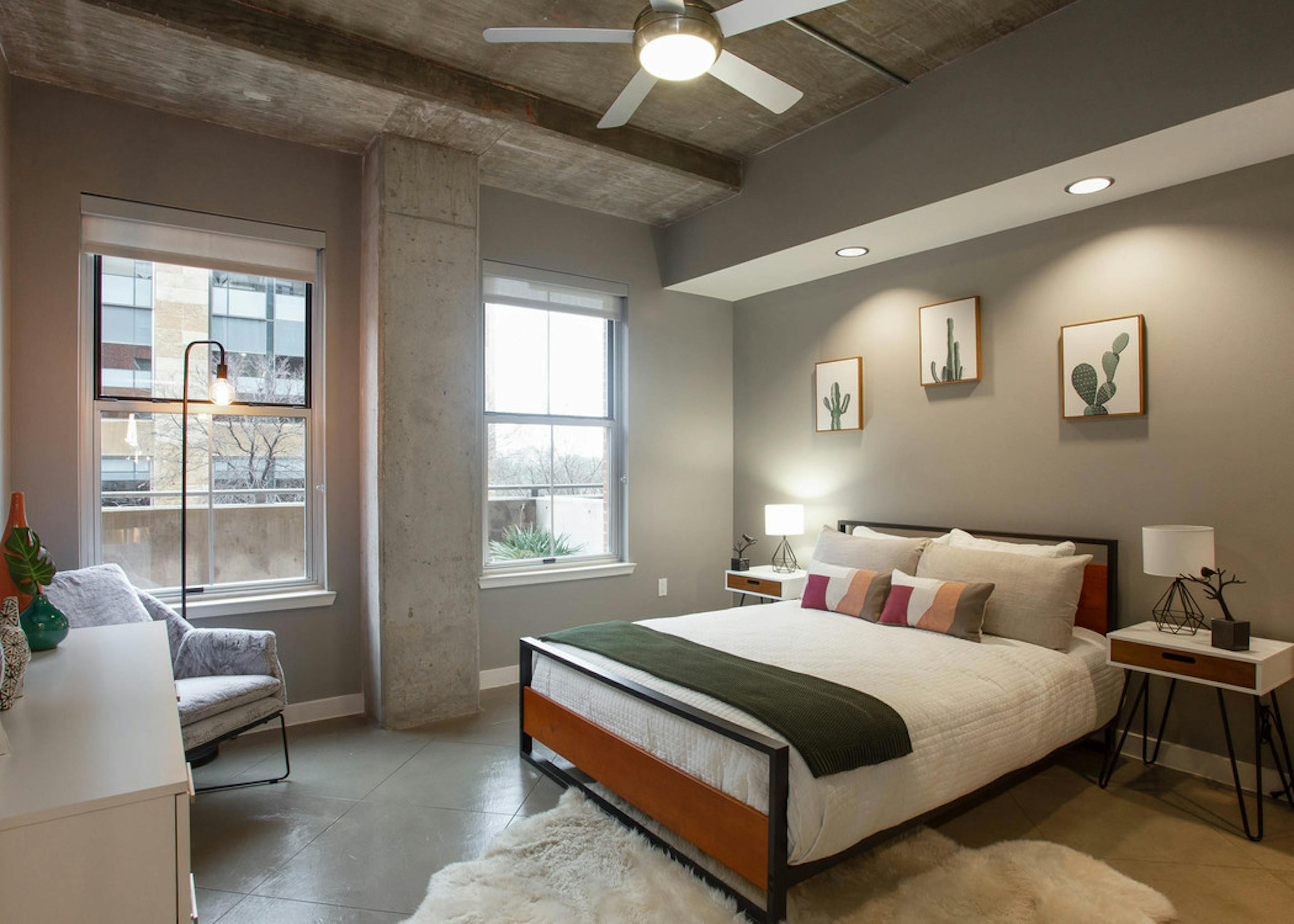 AMLI Downtown bedroom with grey walls and a comfy white bed in front of two large windows with a bright daytime view