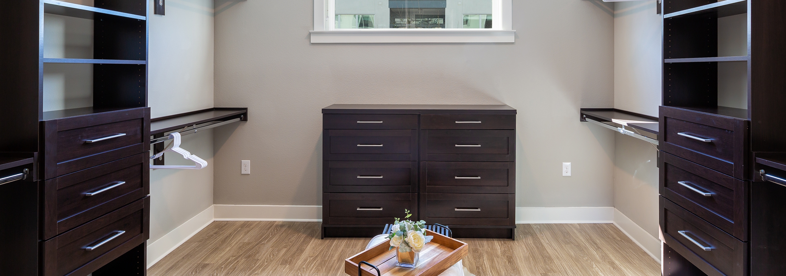 Walk in closet at AMLI South Shore with light hardwood and black built in shelving with plenty of space to hang clothing