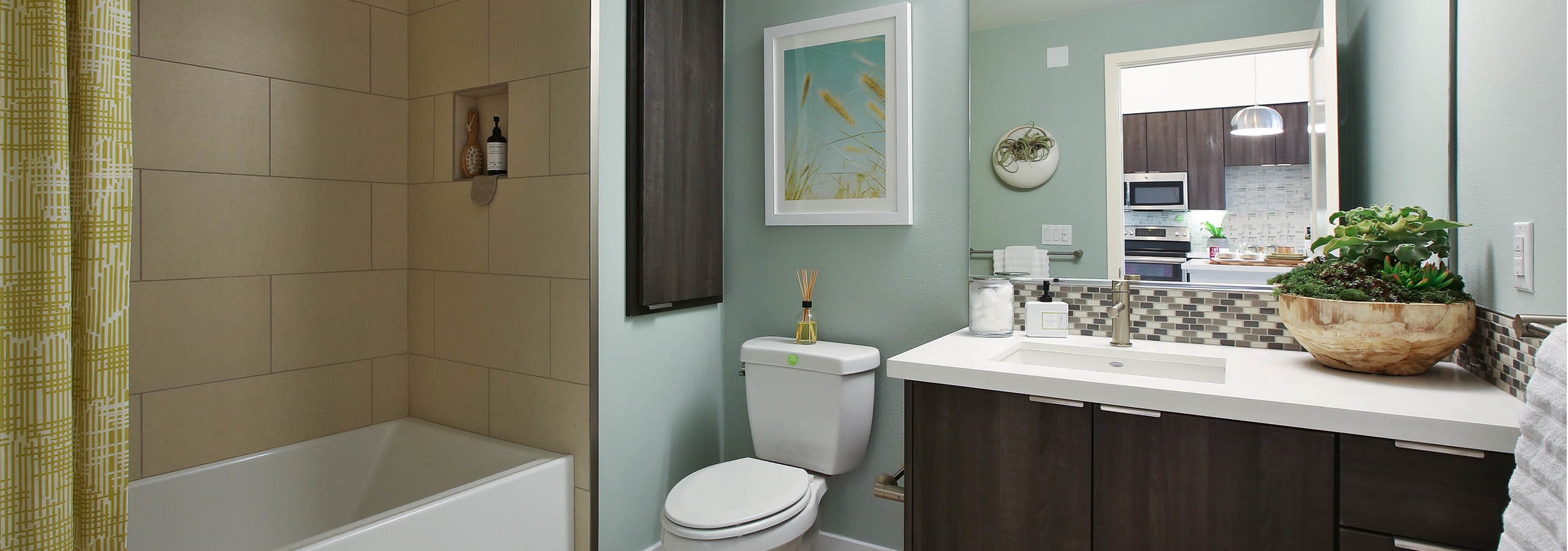 Interior view of AMLI Uptown Orange apartment bathroom with countertop and large soaking tub, tile surround and soap niche