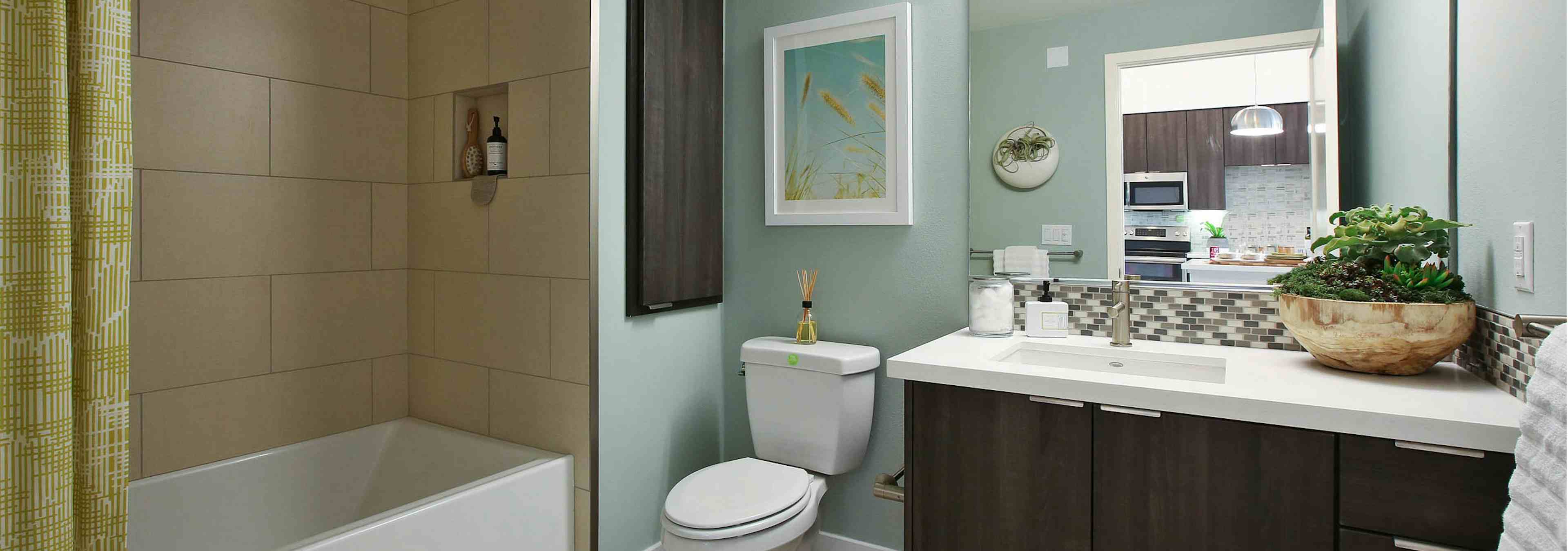 Interior view of AMLI Uptown Orange apartment bathroom with countertop and large soaking tub, tile surround and soap niche