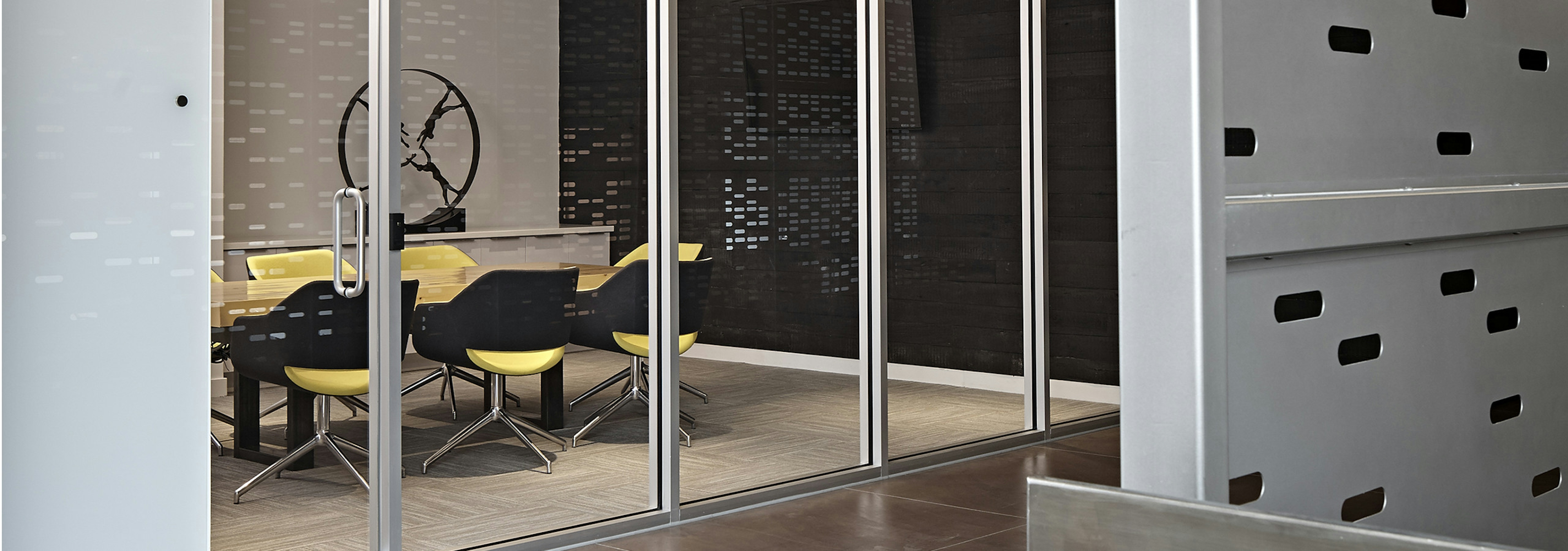 Conference room at AMLI Lofts with a clear glass wall and a conference table paired with bright yellow office chairs