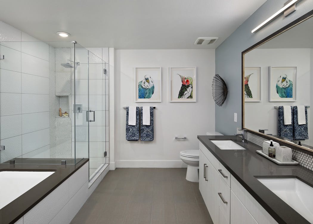 Interior of AMLI Marina Del Rey bathroom with quartz countertop, standing shower with frameless doors, tub and tile flooring