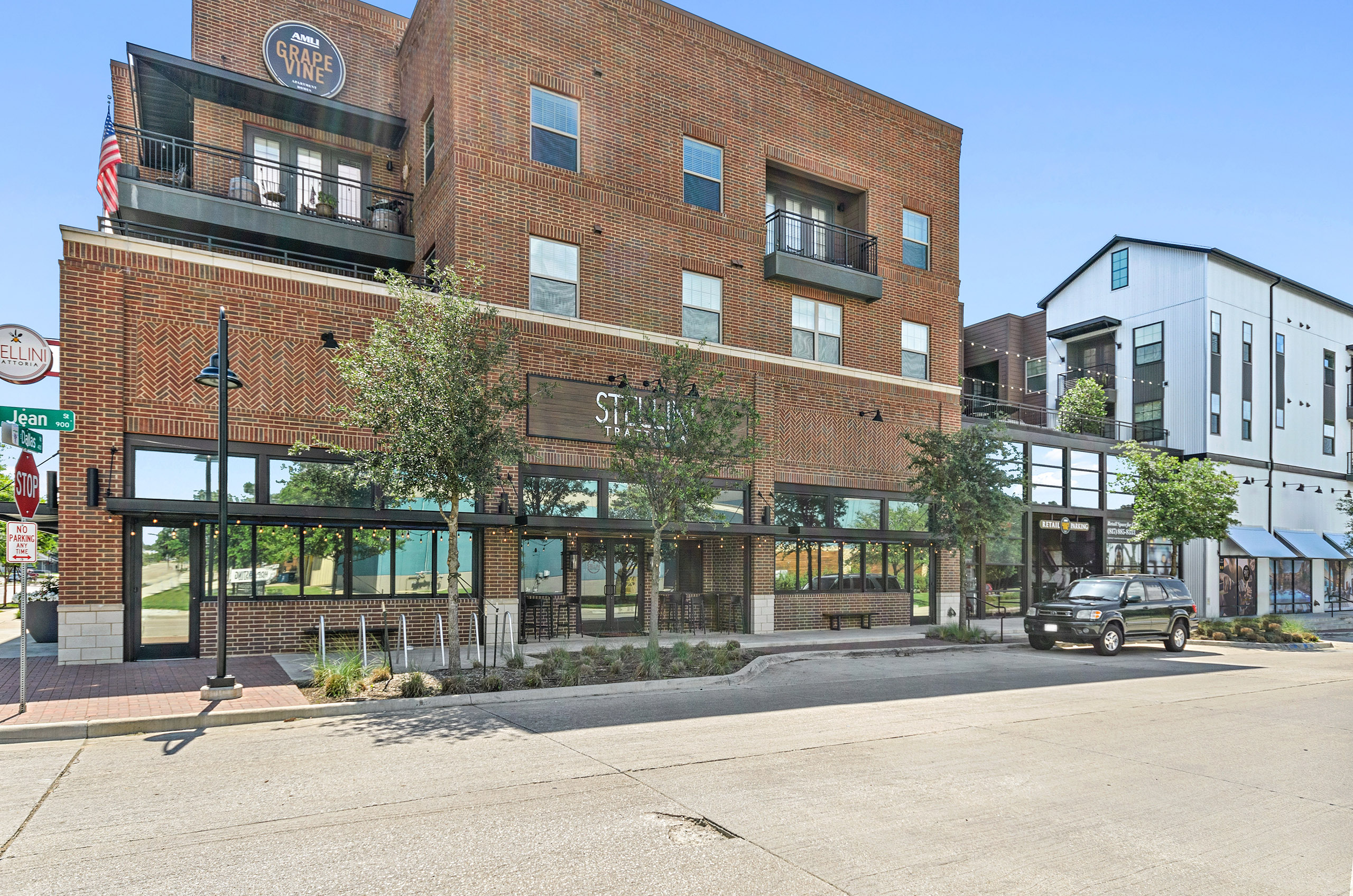 Street view of AMLI Grapevine retail partners with red brick exterior and storefronts framed by outdoor string lights