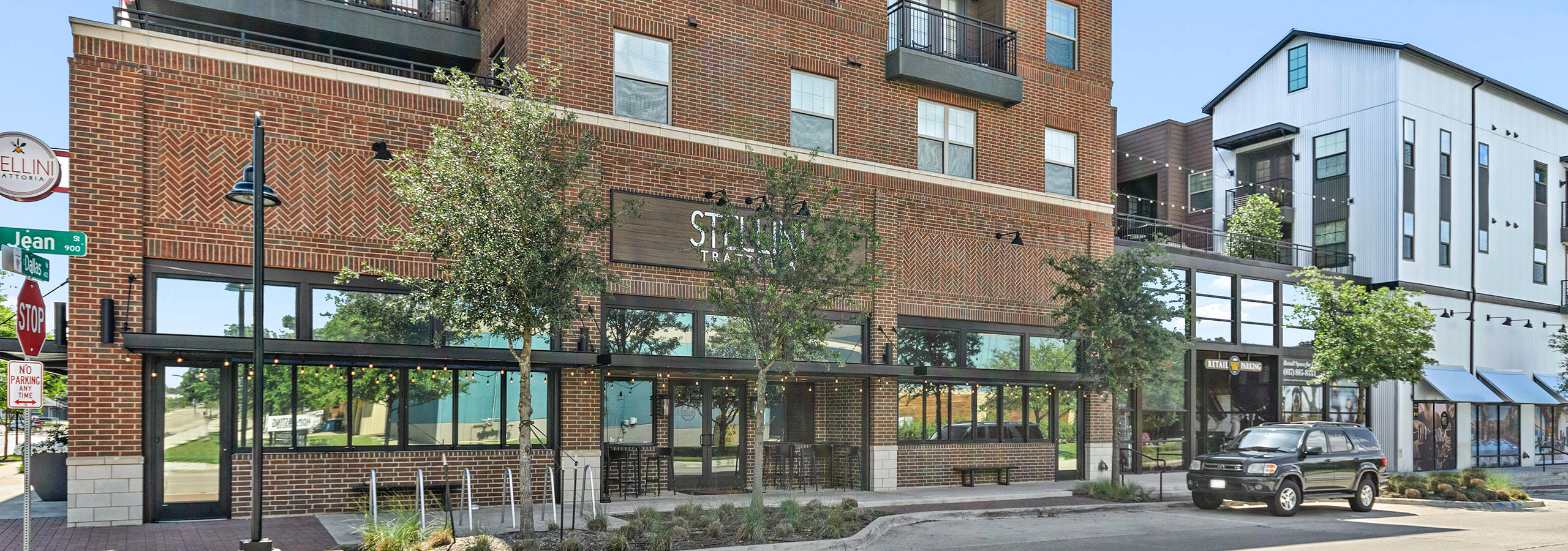 Street view of AMLI Grapevine retail partners with red brick exterior and storefronts framed by outdoor string lights
