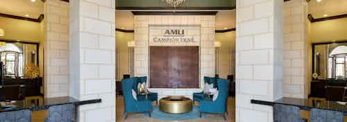 Interior view of clubhouse with and four chairs and round coffee table and desks at AMLI at the Ballpark apartment building