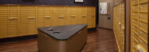 Mailroom at AMLI Riverfront Green apartments with all resident mail boxes and island table with trash receptacles