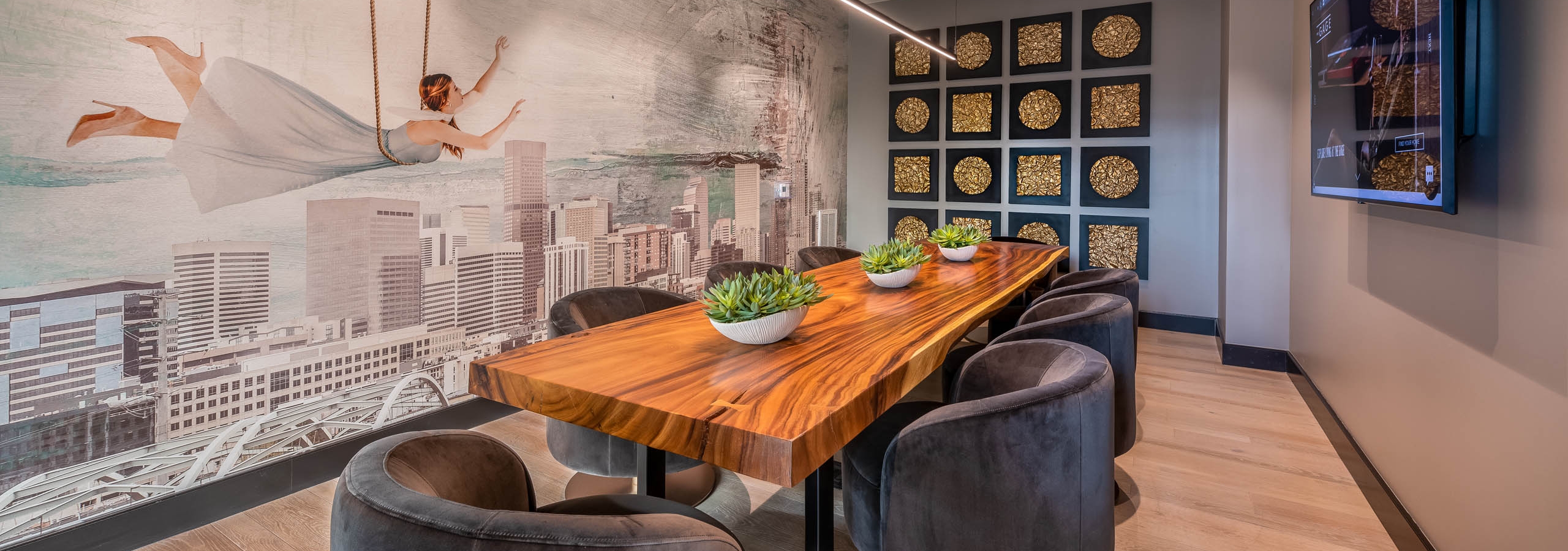 AMLI Art District conference room with a long wooden table and several plush chairs as well as a wall mural and a television
