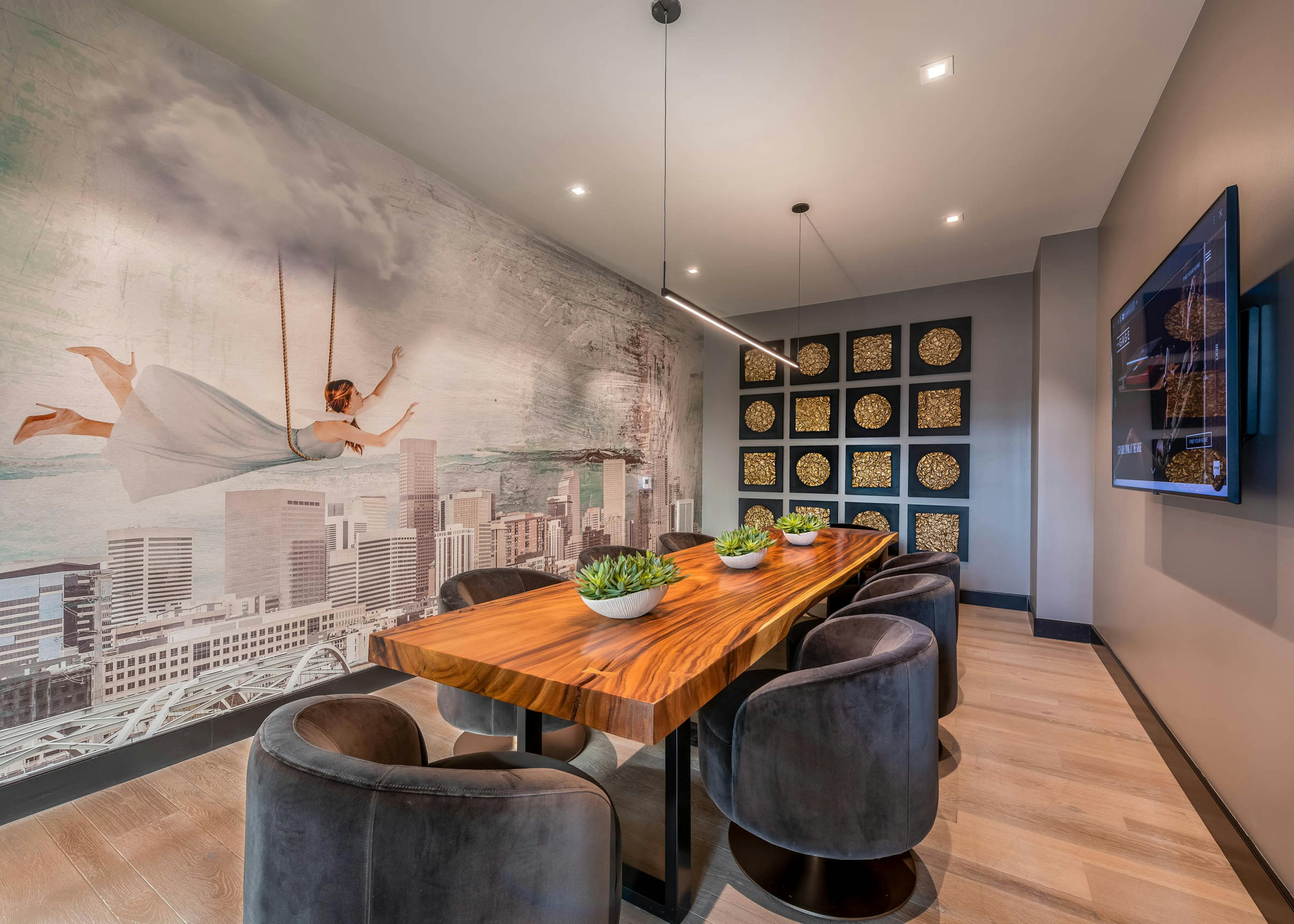 AMLI Art District conference room with a long wooden table and several plush chairs as well as a wall mural and a television