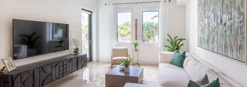 Interior view of an AMLI Park West apartment living area with white sectional sofa and coffee table and TV and 2 windows
