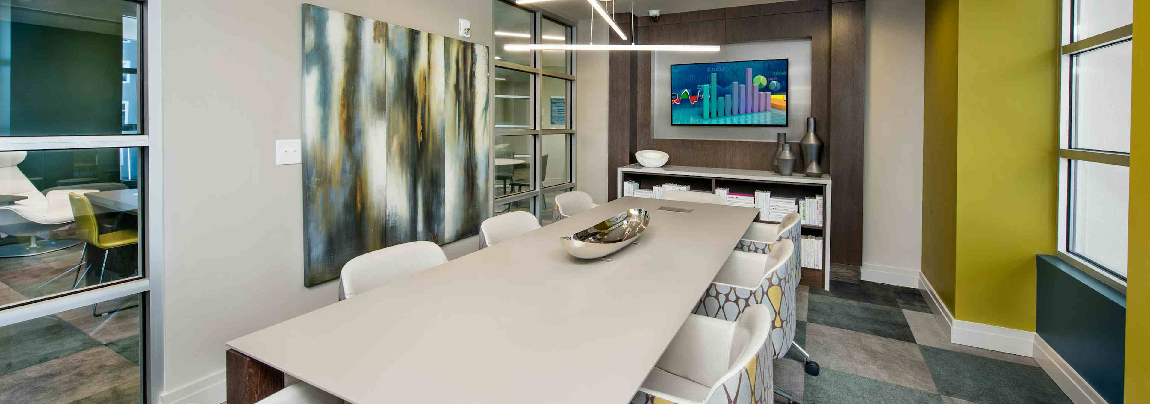 AMLI Buckhead conference room with a long white conference table with patterned chairs and square carpeting with blue shades