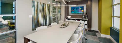 AMLI Buckhead conference room with a long white conference table with patterned chairs and square carpeting with blue shades