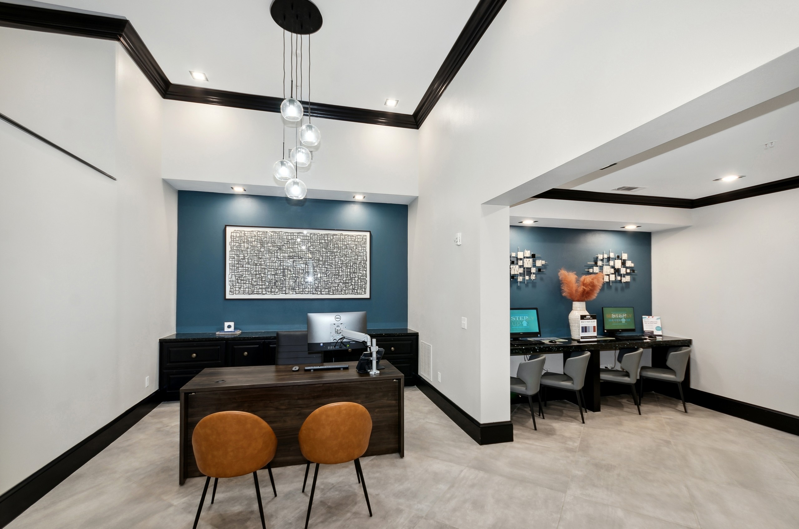 AMLI Campion Trail leasing office with desk facing 2 orange chairs and counter with 2 computer screens and  4 chairs