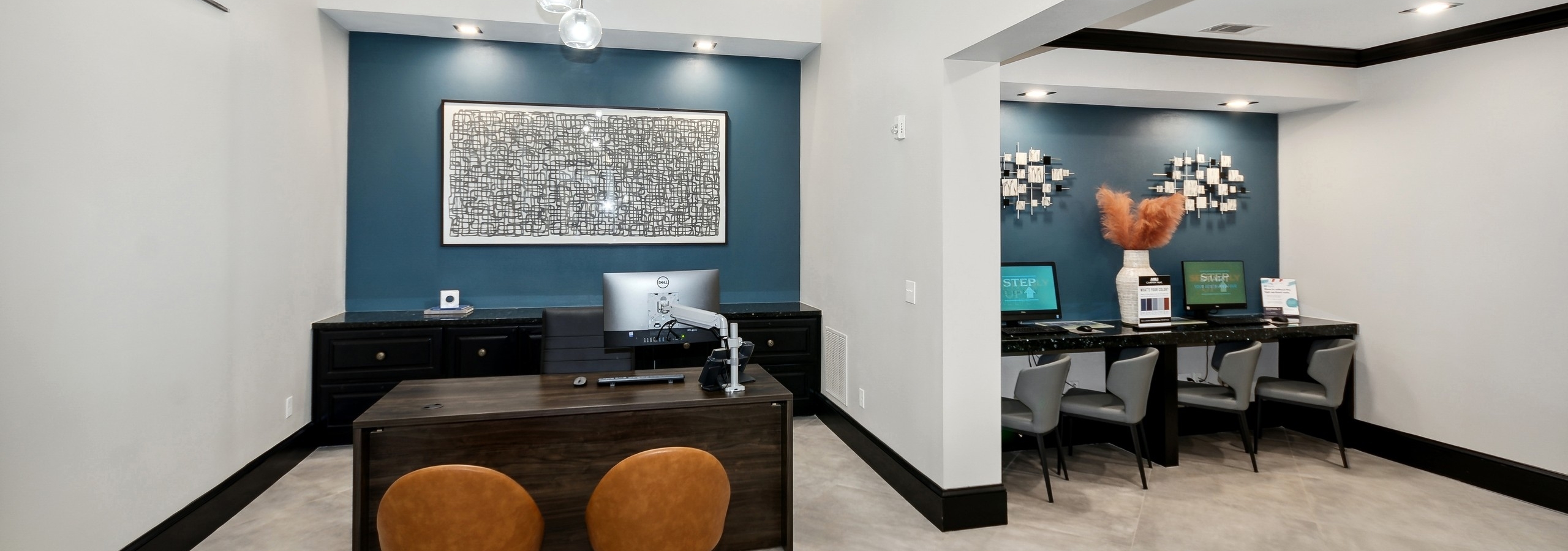 AMLI Campion Trail leasing office with desk facing 2 orange chairs and counter with 2 computer screens and  4 chairs
