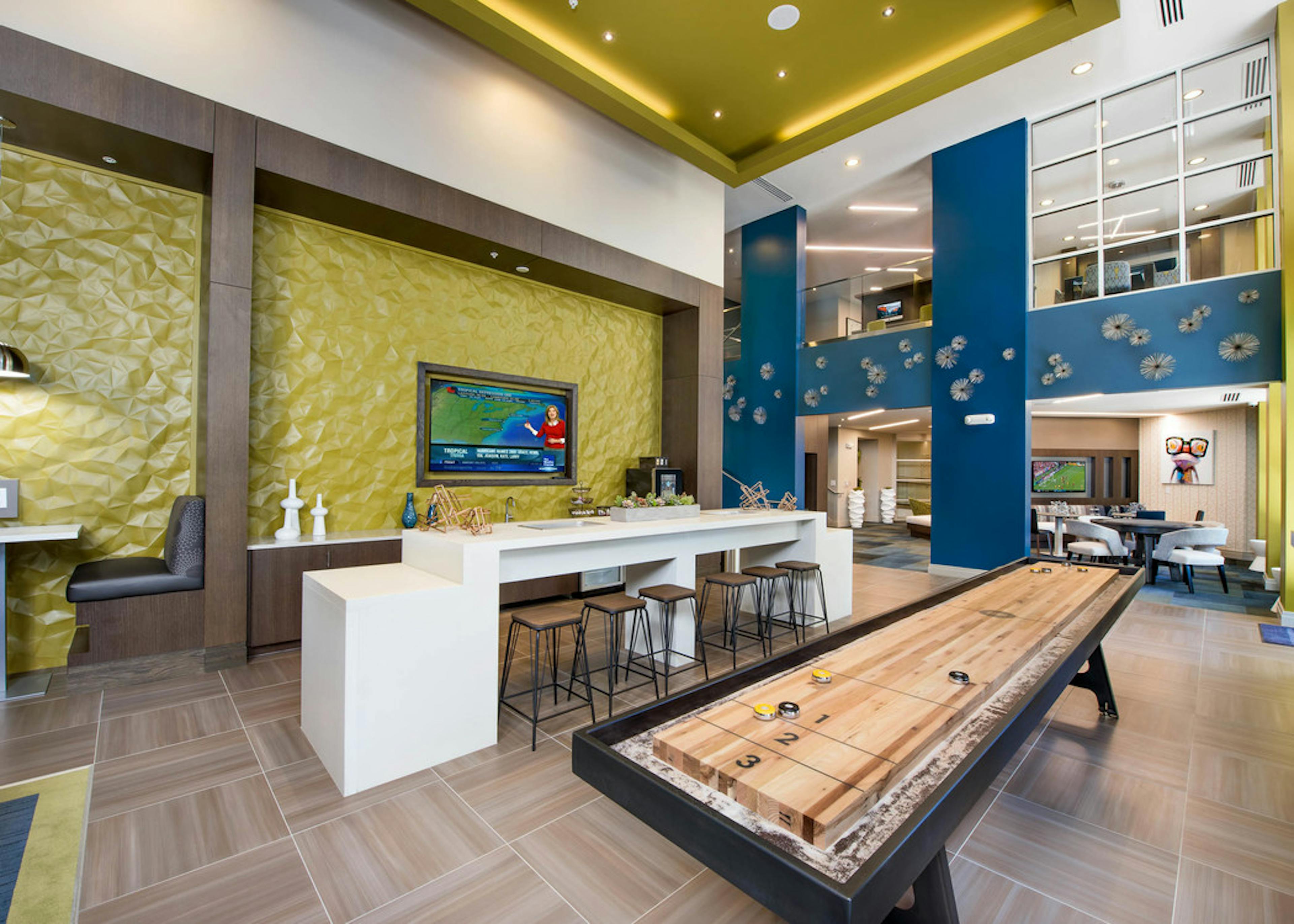 Clubroom at AMLI Buckhead with yellow and blue textured walls and booth seating with a white counter and industrial barstools