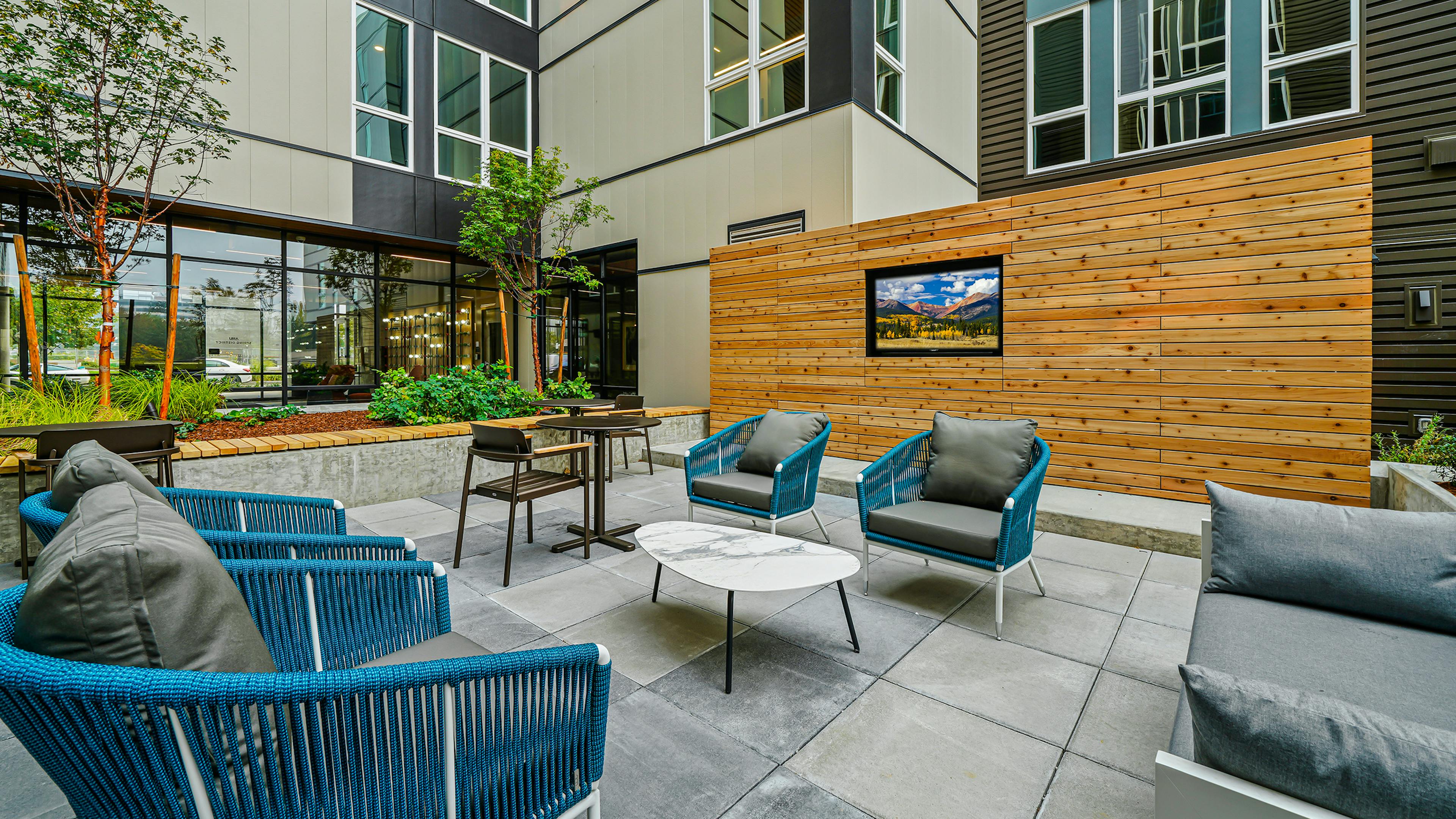Daytime view of AMLI Spring District apartments landscaped courtyard with seating and large TV built into large wood wall