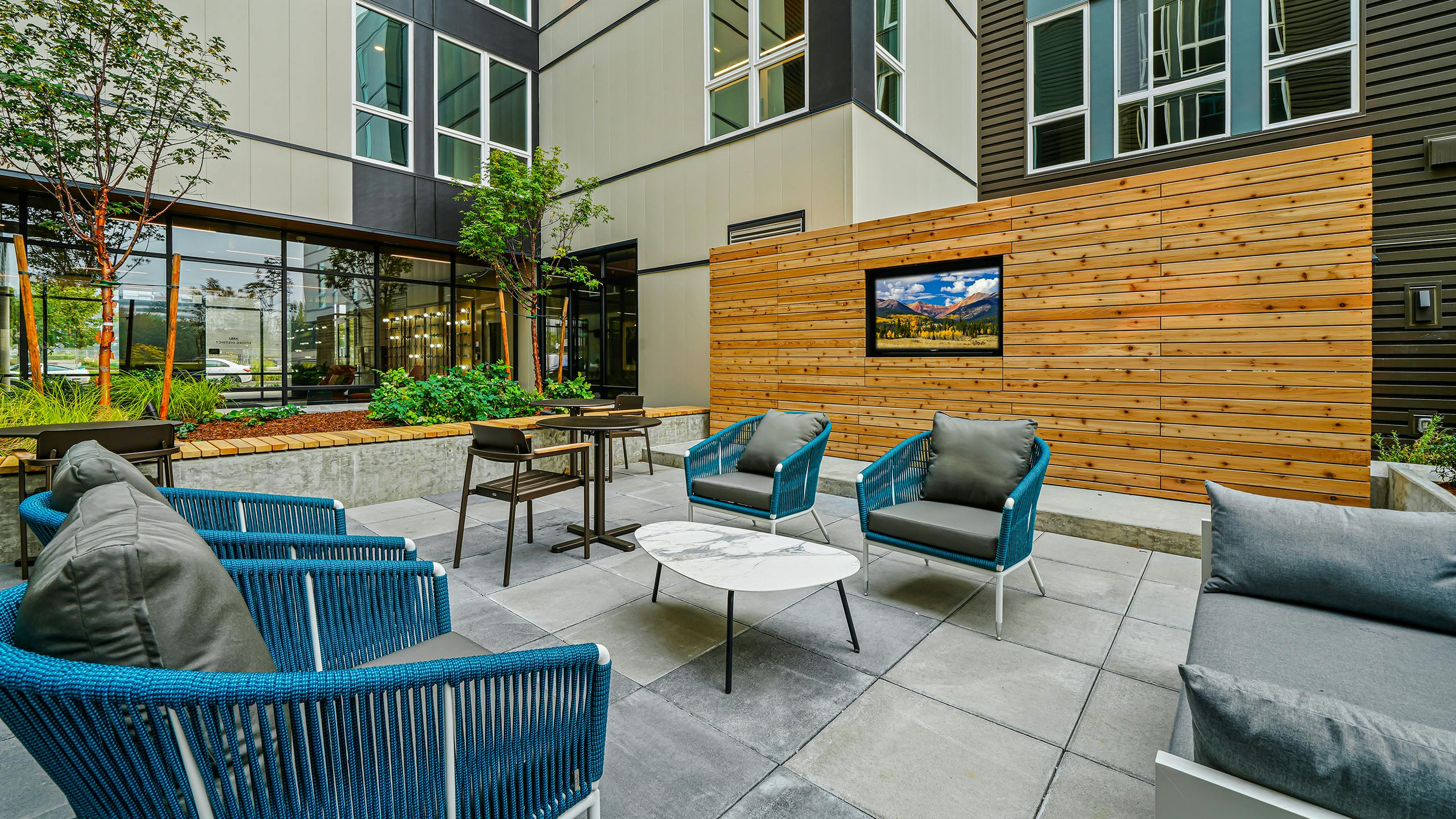 Daytime view of AMLI Spring District apartments landscaped courtyard with seating and large TV built into large wood wall