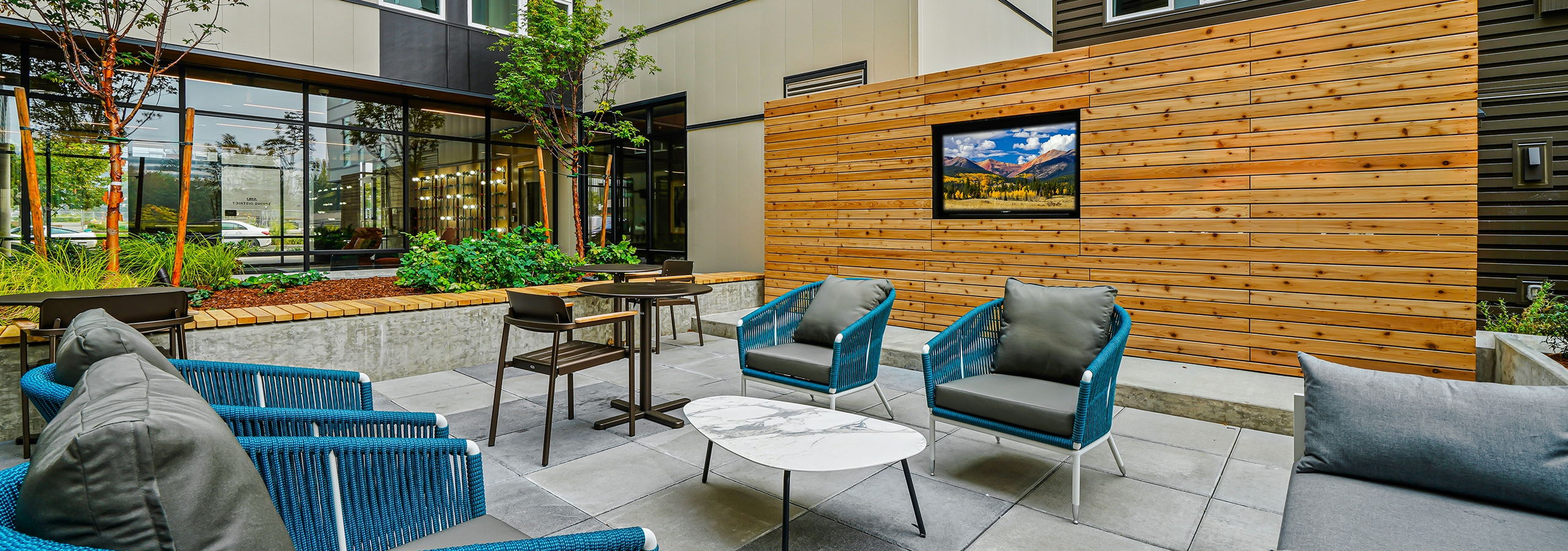 Daytime view of AMLI Spring District apartments landscaped courtyard with seating and large TV built into large wood wall