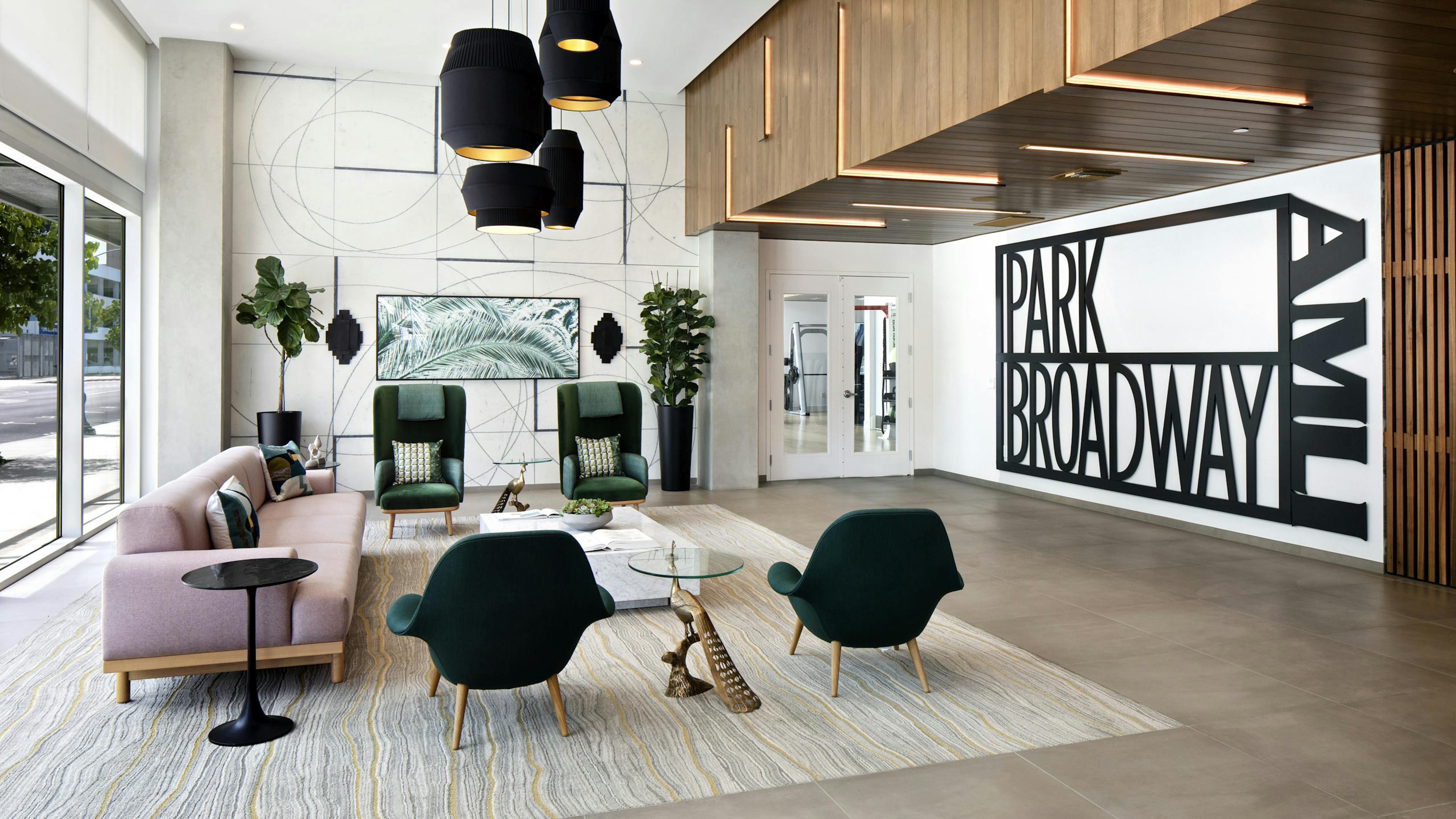 AMLI Park Broadway apartment building lobby with pink couch and four dark green chairs and modern black hanging lights