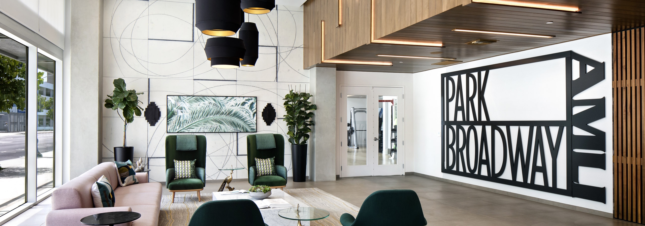 AMLI Park Broadway apartment building lobby with pink couch and four dark green chairs and modern black hanging lights