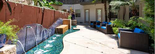 Daytime view of AMLI 300 relaxing zen garden with blue fountains and reclining brown wicker chairs and blue pillows