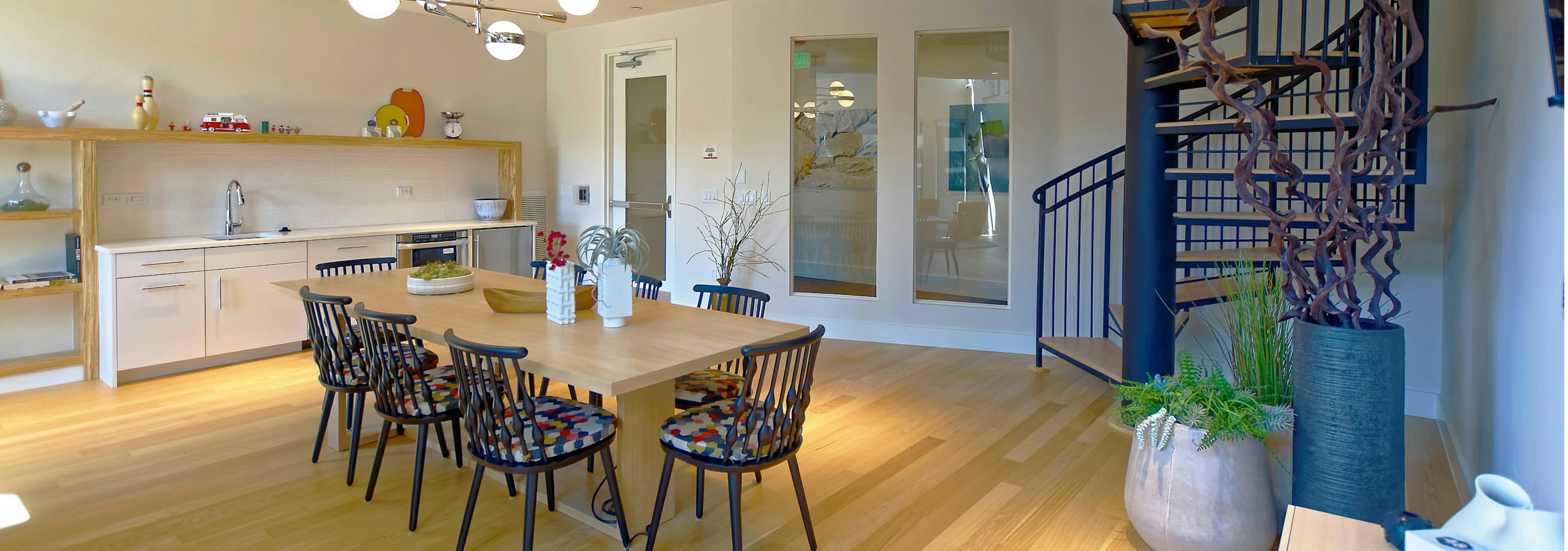 Interior view of a resident lounge at AMLI Dry Creek apartments with a dining table a kitchen area and a spiral staircase 