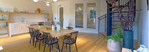 Interior view of a resident lounge at AMLI Dry Creek apartments with a dining table a kitchen area and a spiral staircase