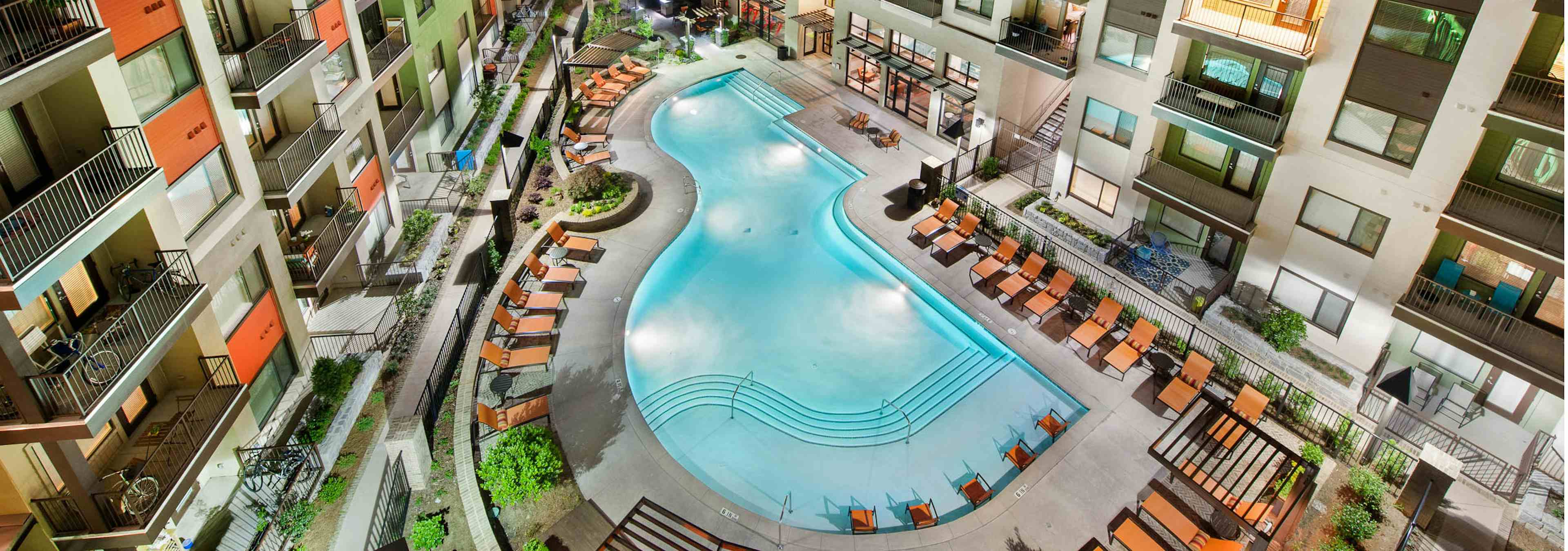 Aerial view of AMLI Ponce Park pool shaped like a teardrop with the apartment building and lounge chairs surrounding it