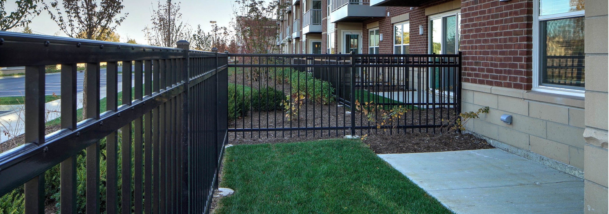 Exterior view of first floor private fenced in patio and lawn in the daytime light at AMLI Deerfield apartment community