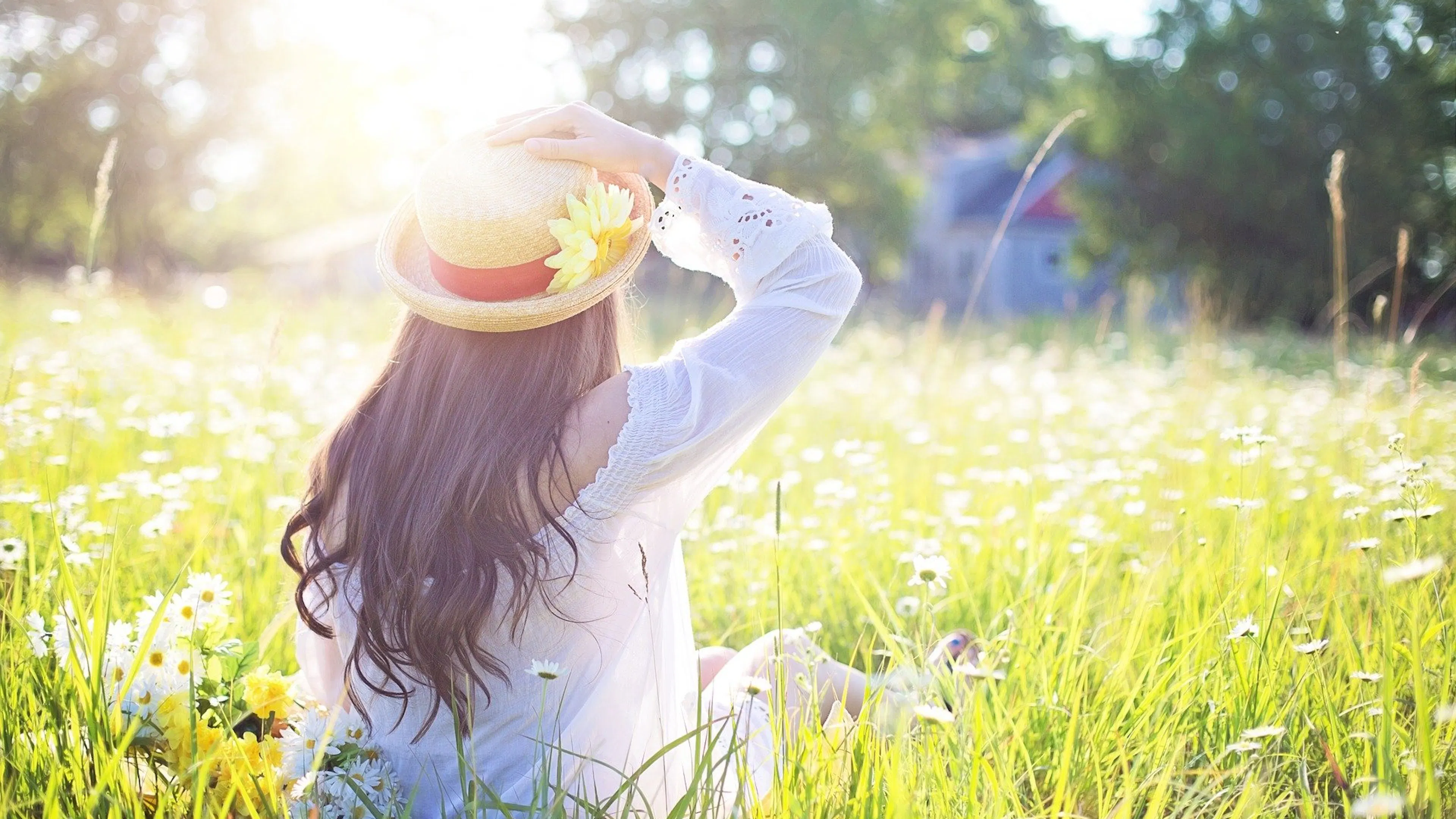 woman in field holding hat in sunlight