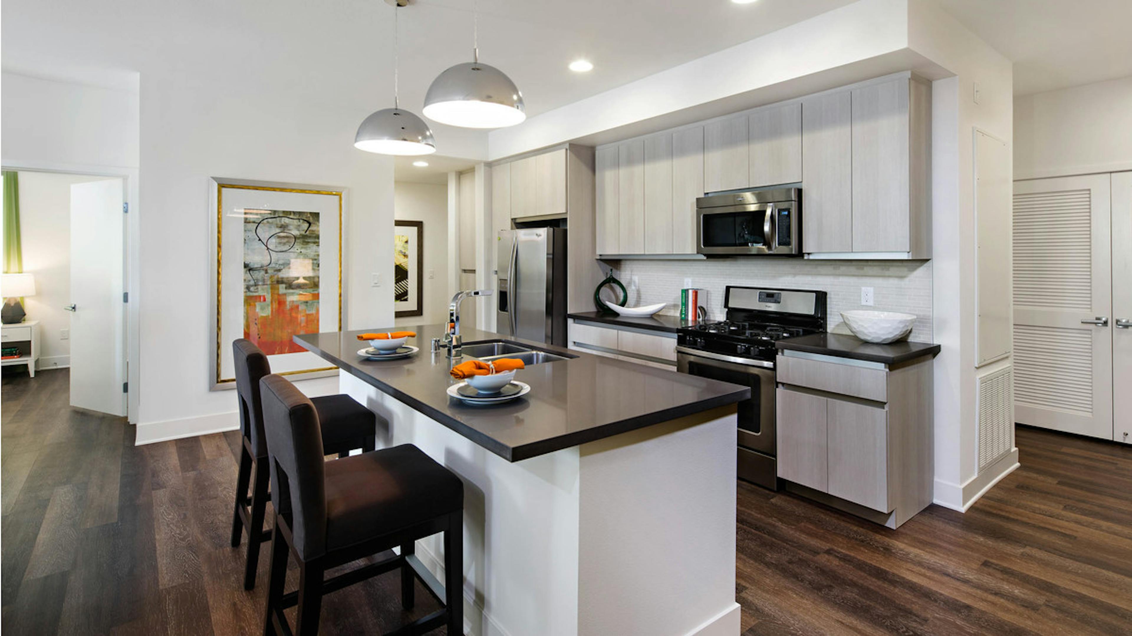 AMLI Lex on Orange apartment kitchen with light cabinetry, stone designer backsplash with quartz countertops and appliances