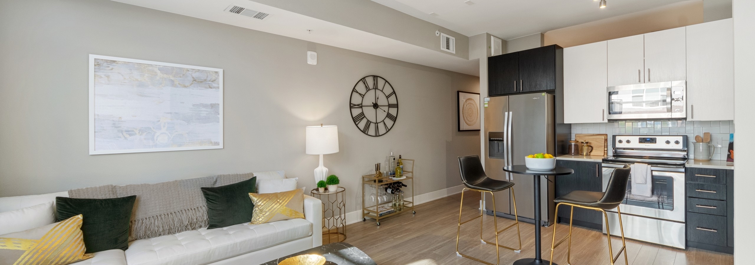 AMLI Riverfront Green living and kitchen area featuring light flooring and black and white furnishings with gold accents