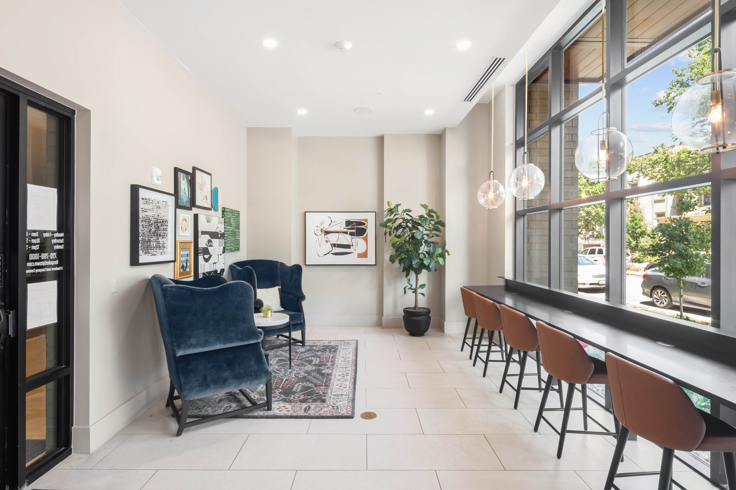 AMLI at Uptown ride share lounge with velvet chairs and leather stools at a sleek counter running against floor to ceiling windows 