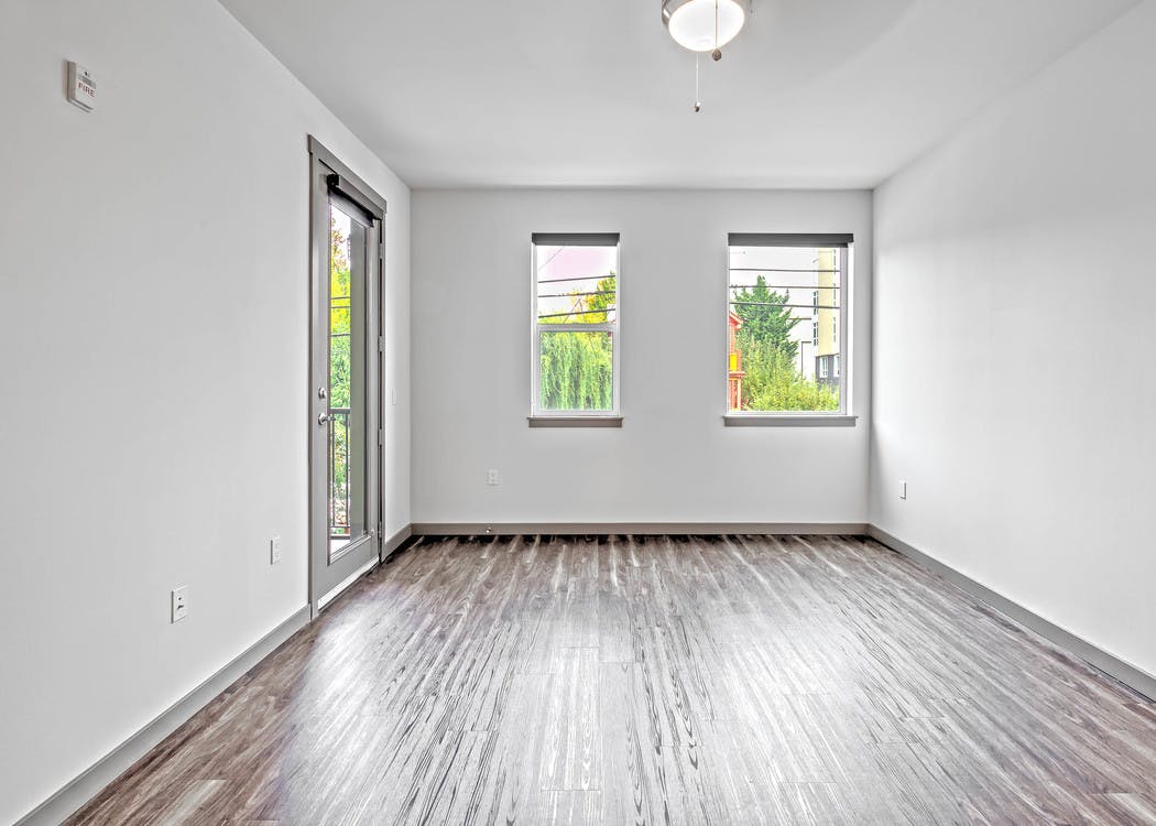 Interior view of AMLI Mark24 living room with laminate floor large windows white walls and door to patio