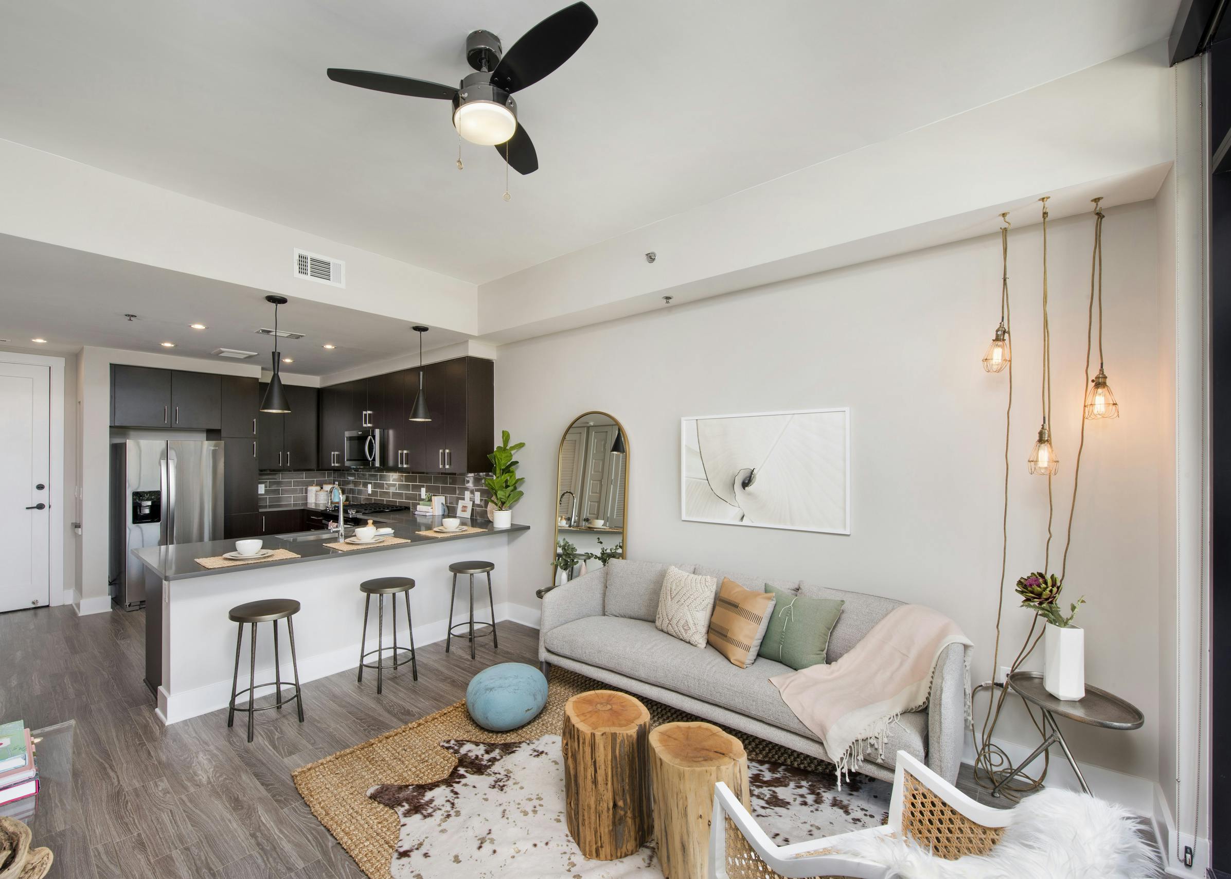 Interior of AMLI Lenox apartment with light sofa and hanging lights and three bar stools at an island overlooking the kitchen
