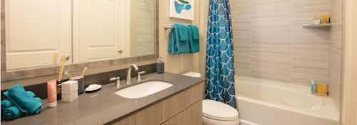 Interior of a bathroom at AMLI Dry Creek apartments with granite counter top and stainless steel fixtures and blue linens