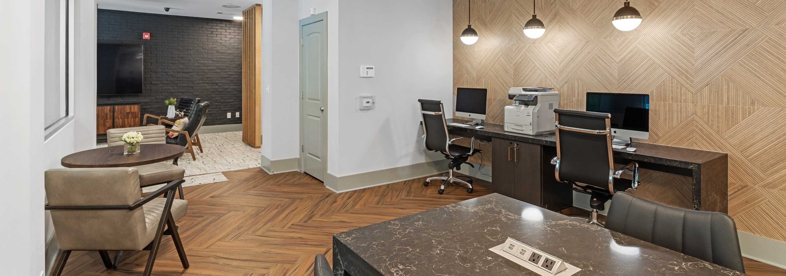 Interior view of the business center at AMLI North Point with computer stations and desk chairs with wood panel accent wall