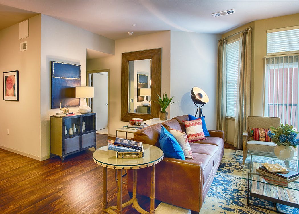 Interior view of a living room at AMLI Denargo Market apartments with lamps and a couch and chair and a look in the bedroom