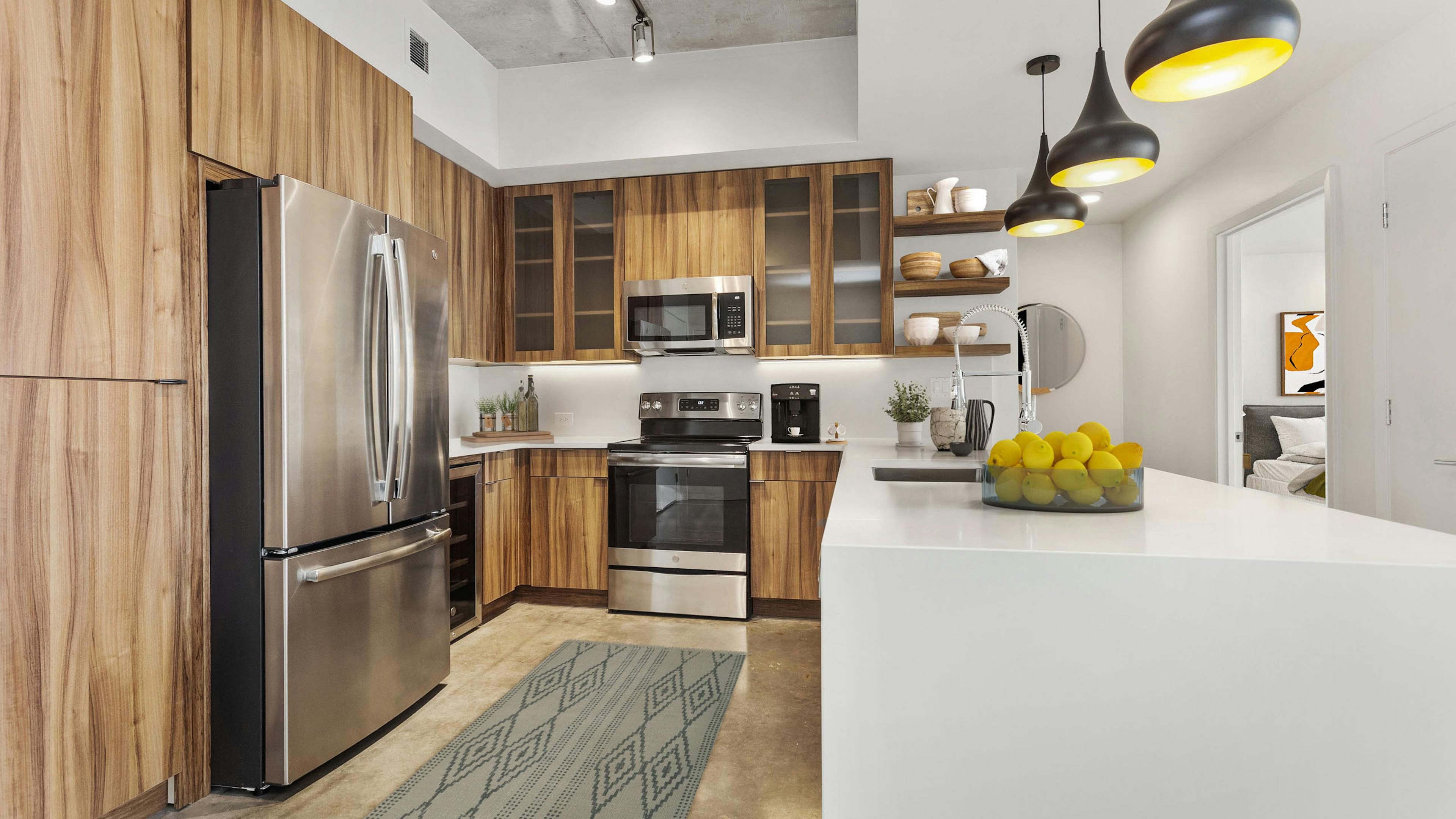 View of kitchen at AMLI on 2nd with concrete flooring and wood cabinets and stainless steel appliances with white countertops