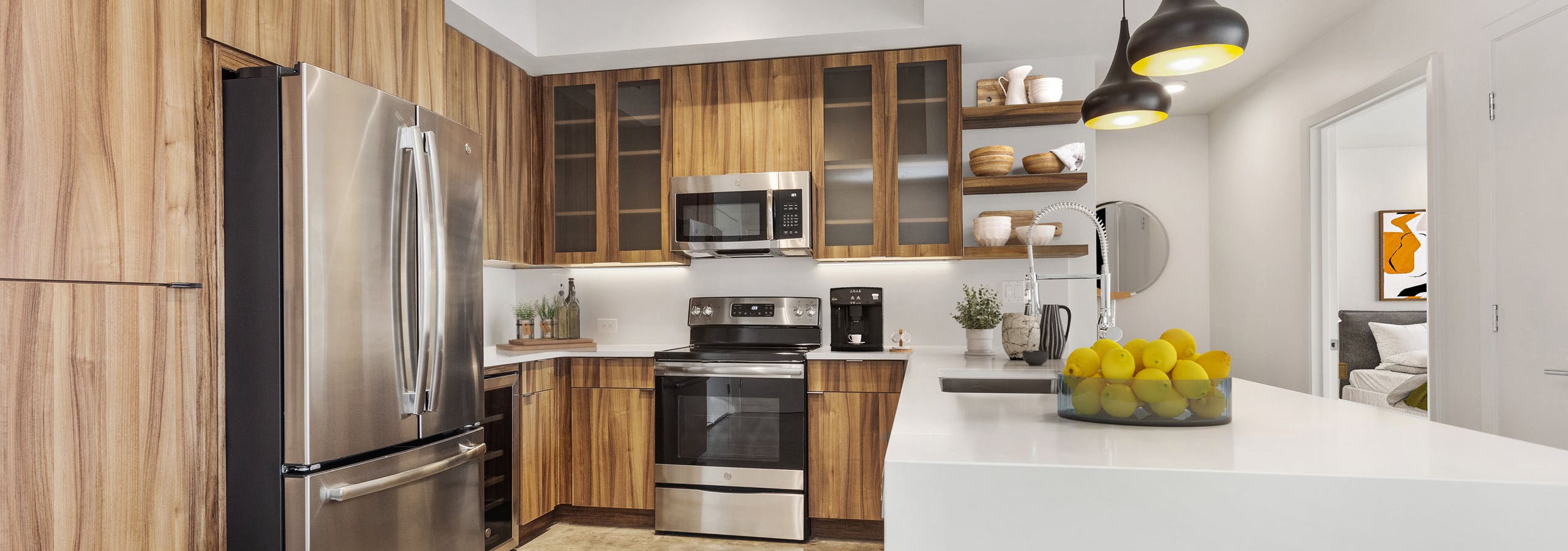 View of kitchen at AMLI on 2nd with concrete flooring and wood cabinets and stainless steel appliances with white countertops