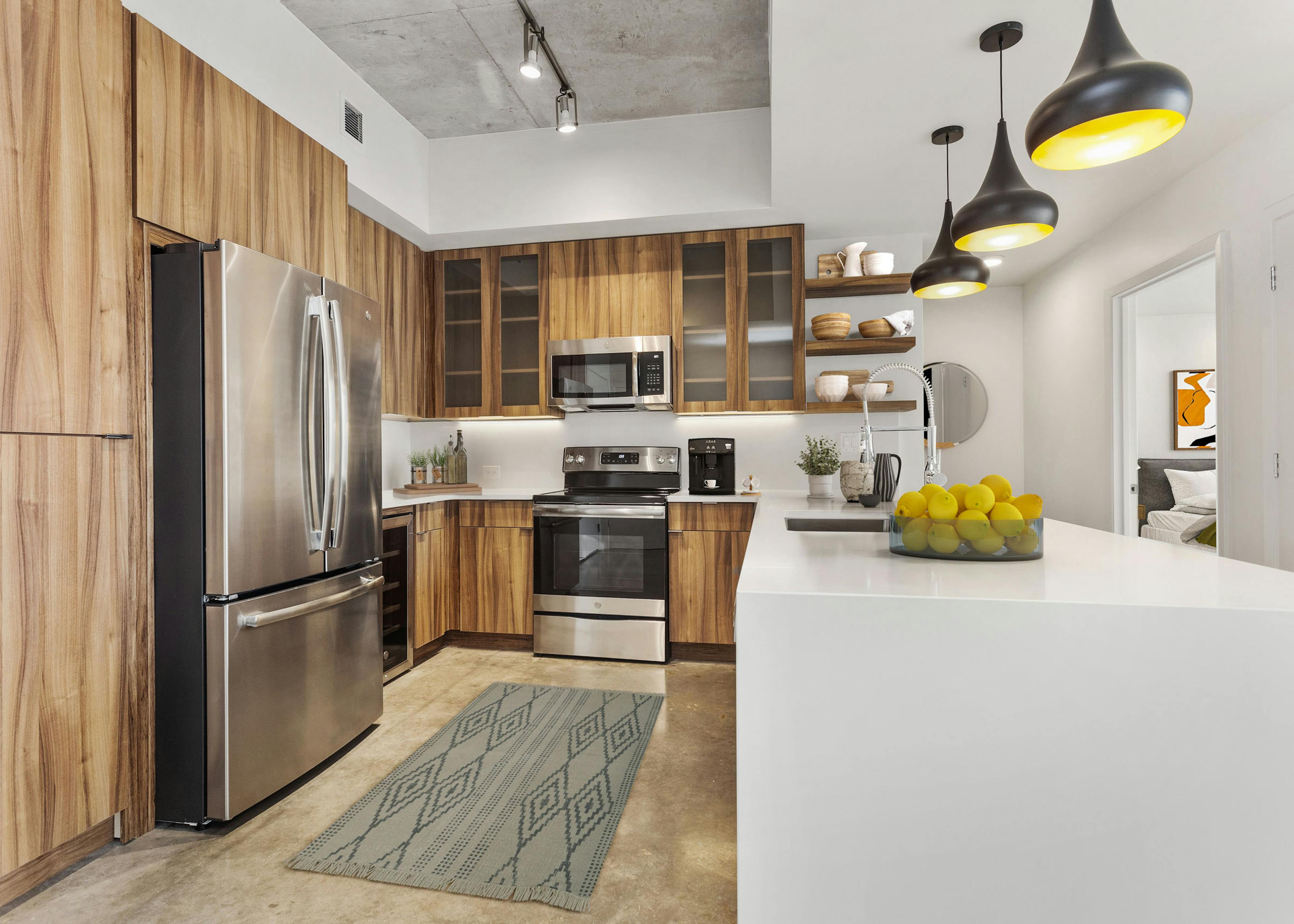 View of kitchen at AMLI on 2nd with concrete flooring and wood cabinets and stainless steel appliances with white countertops