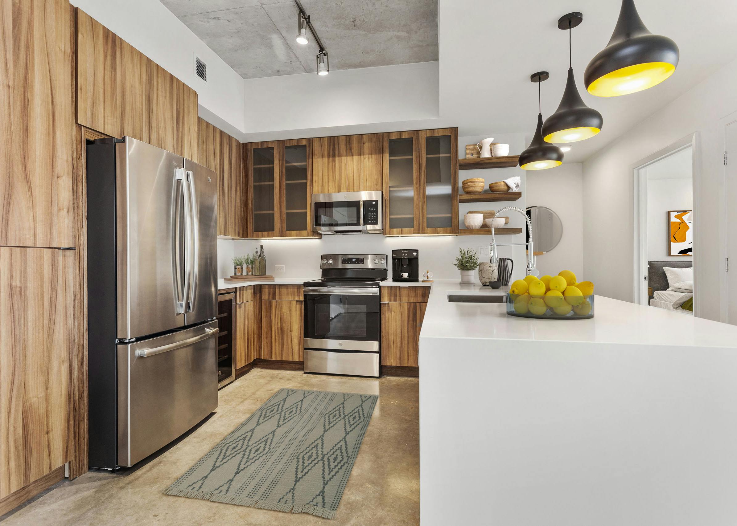 View of kitchen at AMLI on 2nd with concrete flooring and wood cabinets and stainless steel appliances with white countertops